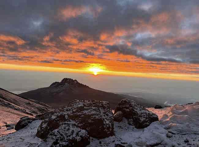 Sunrise above the clouds from the upper slopes of Kilimanjaro, with Mawenzi peak in silhouette